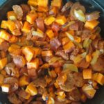 Chopped sweet potatoes, onion and vegetarian sausage in a cast iron pan