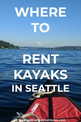A kayak bow on a lake surrounded by forested hills with houses. Mt Rainier is in the background on a sunny summer day. Text reads: Where to Rent kayaks in Seattle