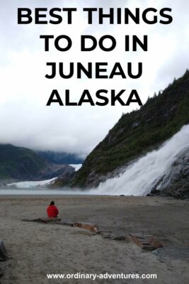A person in a red rainjacket sits on a rock in a sandy plain. In front of the person is a roaring waterfall over a rocky mountainside. In the distance a glacier and a lake can be seen. Text reads: Best things to do in Juneau Alaska