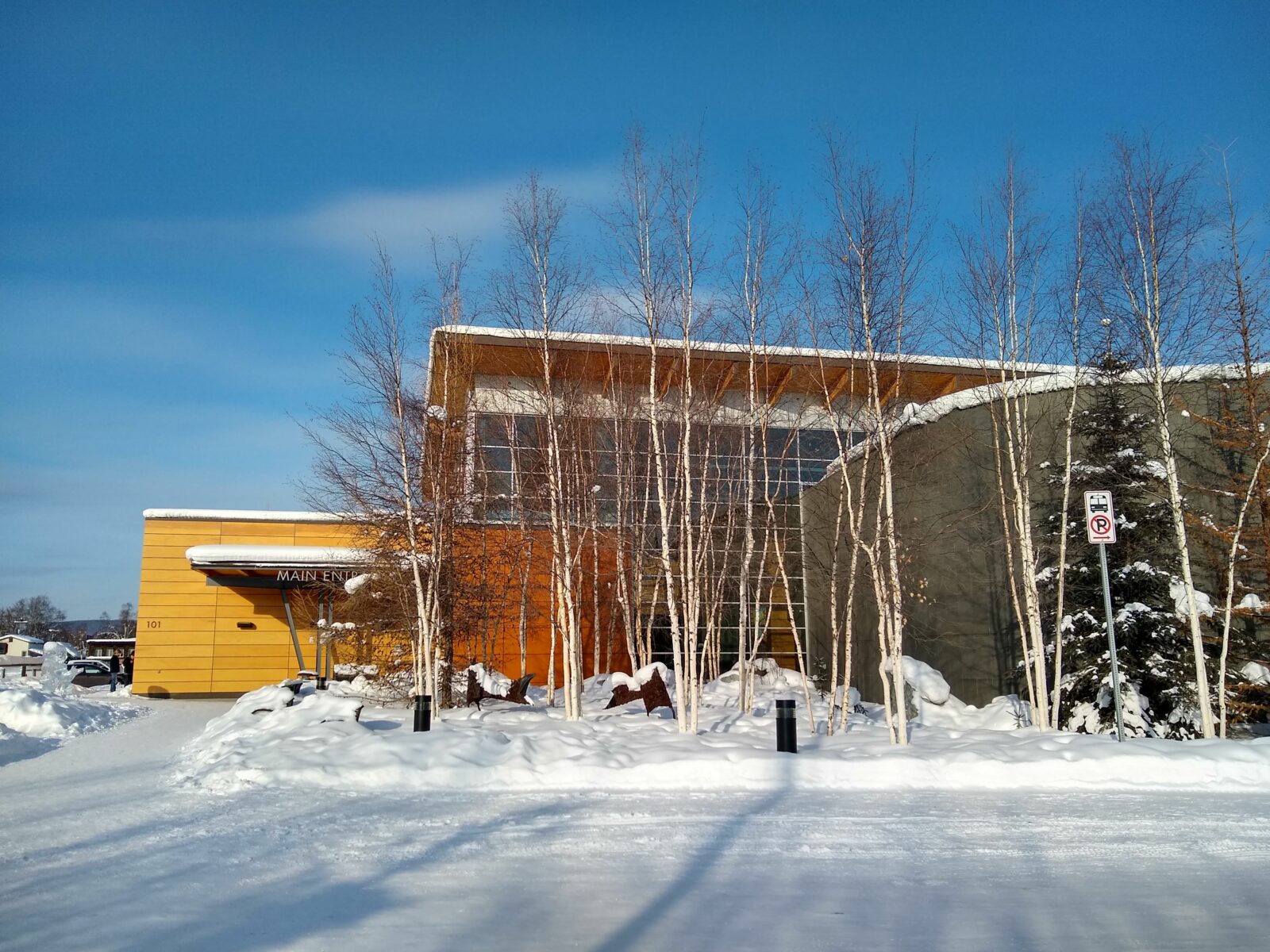 a modern wood and glass building surrounded by snow on a sunny day, the Morris Thompson Cultural Center is a great place to get information about things to do in Fairbanks as well as about the culture of Fairbanks
