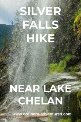 The spray of a waterfall in front of a black rock cliff. Some of the rocks are covered in moss. Text reads: Silver Falls hike near Lake Chelan