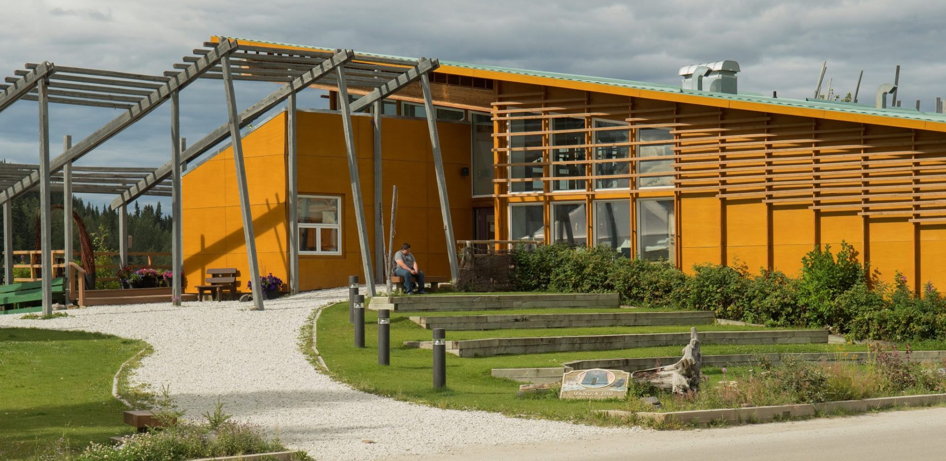 A modern wood and steel building with big windows and landscaping with a path around it