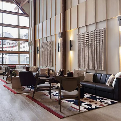 Chairs and sofas on an area rug in the lobby of a building with a big window